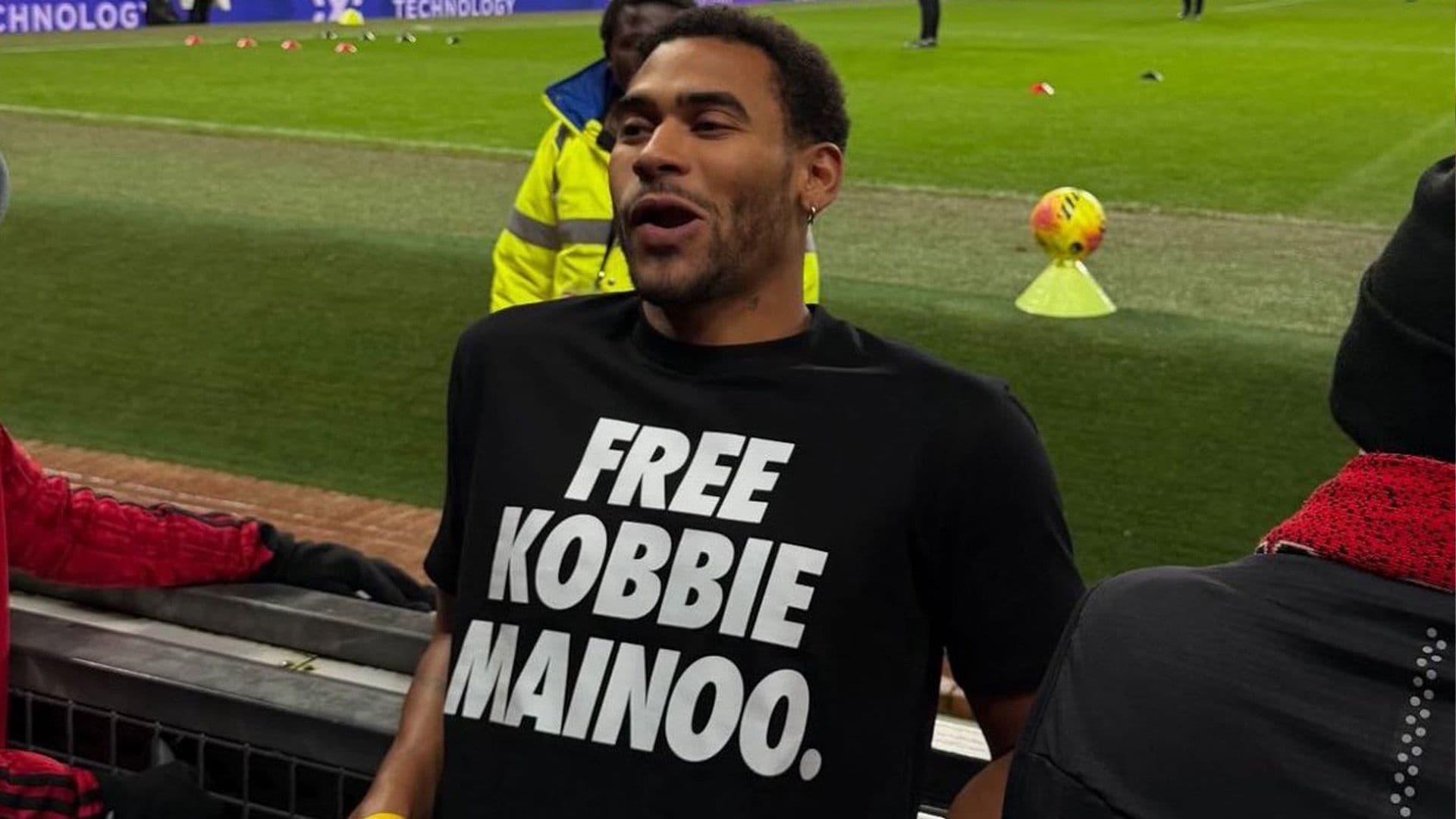 KOBBIE MAINOO’S BROTHER SPARKS DEBATE WITH ‘FREE KOBBIE MAINOO’ T-SHIRT AT OLD TRAFFORD